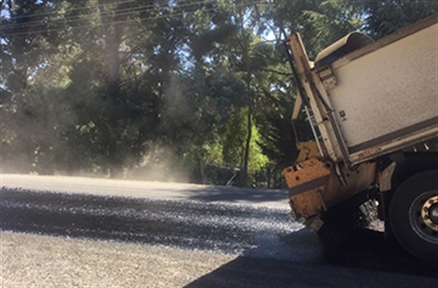 Machinery laying steaming asphalt on a road