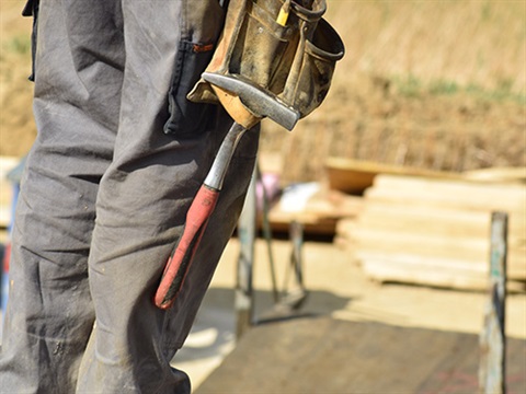 Person building site with hammer in tool belt