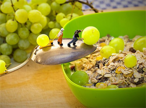 miniature people rolling grapes into a bowl