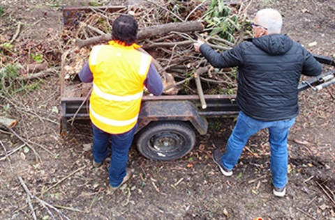 Two people removing green waste from a trailer at the transfer station