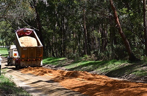 A truck tipping gravel onto a country road