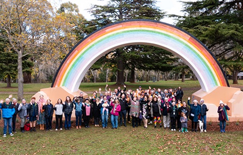 A large group standing under the Big Rainbow in Daylesford