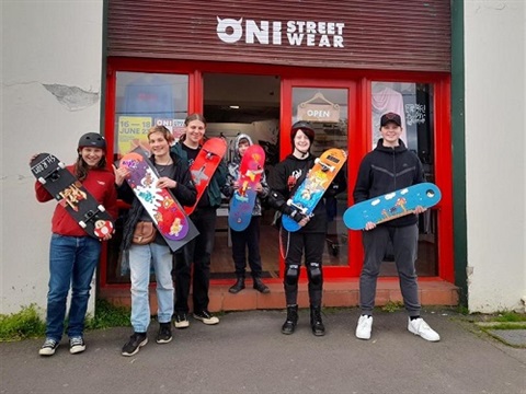 Young people holding decorated skateboard decks