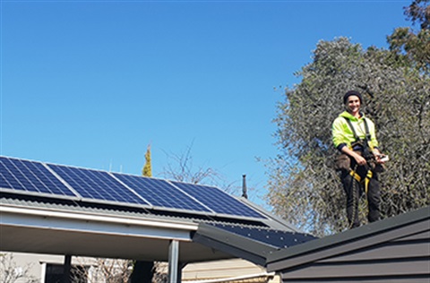 Man standing on top of a roof installing solar panels