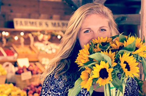 Woman holding sunflower covering some of her face